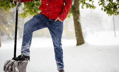 closeup-shot-fo-male-with-his-foot-snow-shovel-while-standing-snowy-field 1